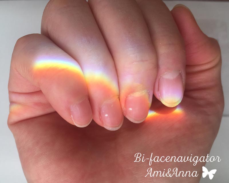 中指と薬指の爪の白点と手に映った太陽のプリズム