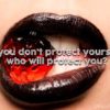 ガラスでできた苺を黒い口紅を塗った女性が唇で咥えている写真